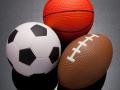 A soccer ball, a basketball, and a football