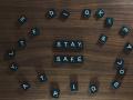 Black scrabble pieces arranged to spell "Stay Safe" with miscellaneous pieces surrounding