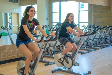 Cycling Machines Recreation Center Students smiling while cycling on cycling machines in the SSU Recreation Center