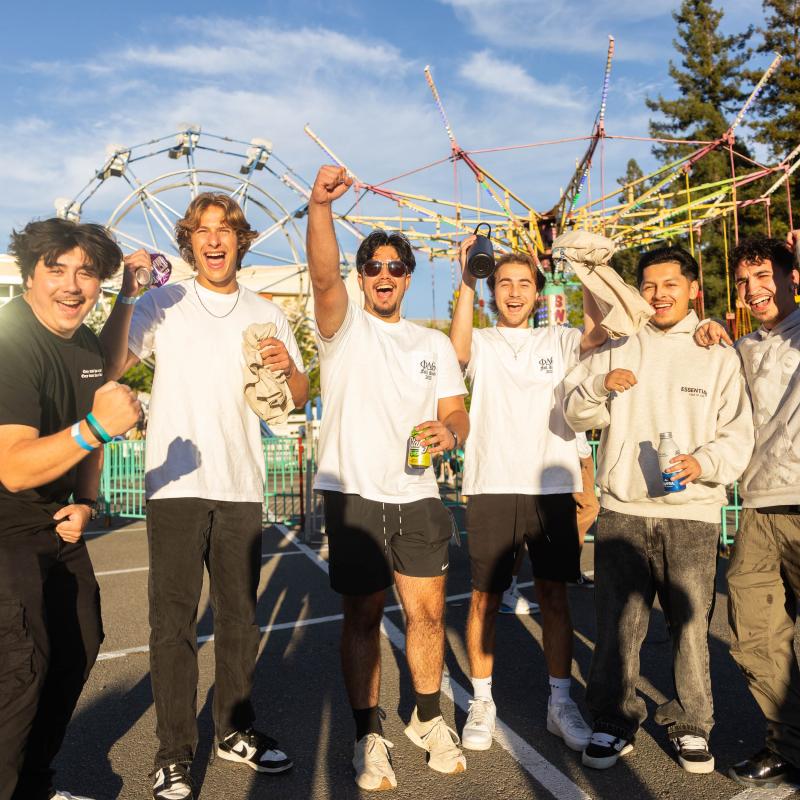 Group of students cheering at Big Nite with Ferris Wheel in background