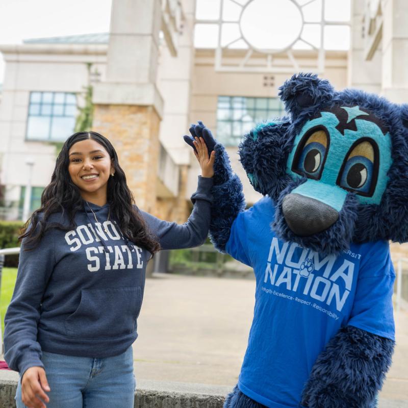 Student high fiving Lobo the mascot