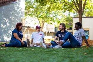 Four students talk while seated outdoors 